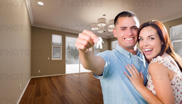 Young military couple with house keys in empty room of new home