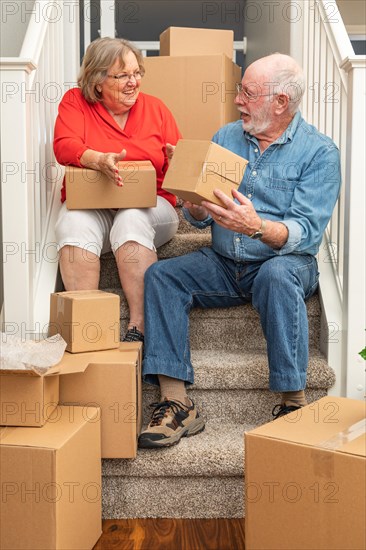 Senior couple resting on stairs surrounded by moving boxes