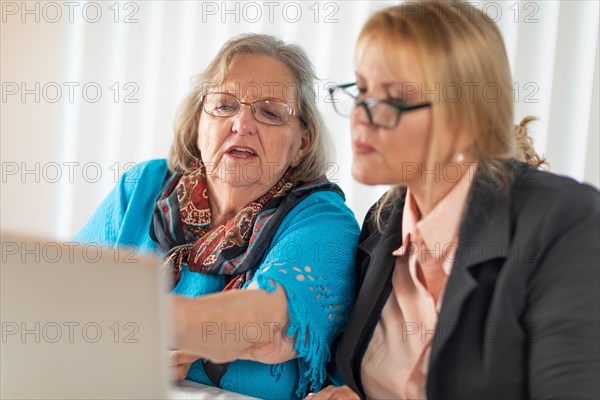 Woman helping senior adult lady on laptop computer