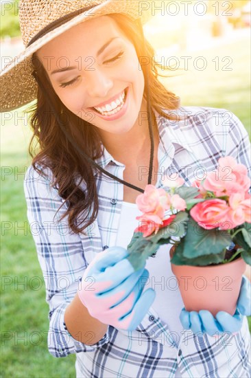 Happy young adult woman wearing hat and gloves gardening outdoors