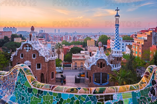 Barcelona city view from Guell Park with colorful mosaic buildings in tourist attraction Park Guell in the morning on sunrise