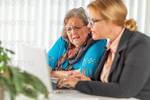 Woman helping senior adult lady on laptop computer