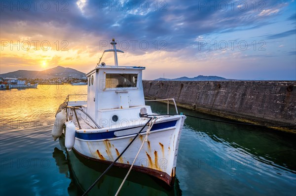 Old fishing boat in port of Naousa on sunset with dramatic sky. Paros lsland
