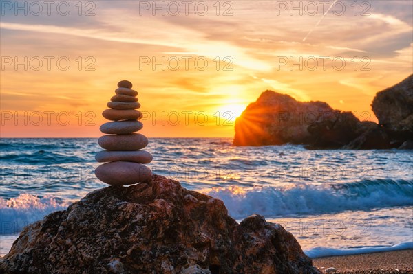 Cairn stack of stones pebbles cairn on the beach coast of the seaon sunset