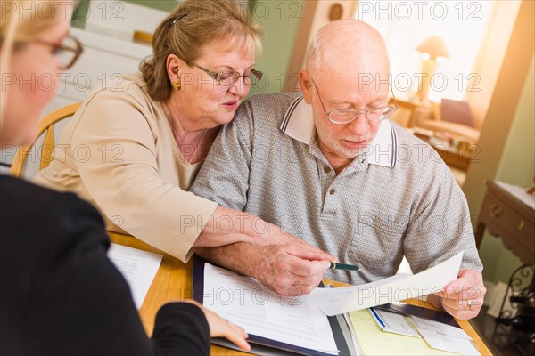 Senior adult couple going over documents in their home with agent at signing