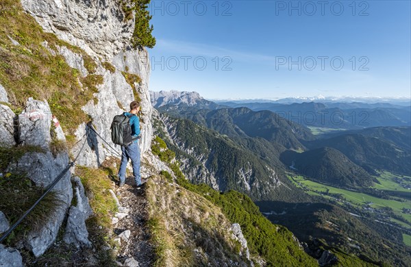 Hiker on hiking trail with steel cable