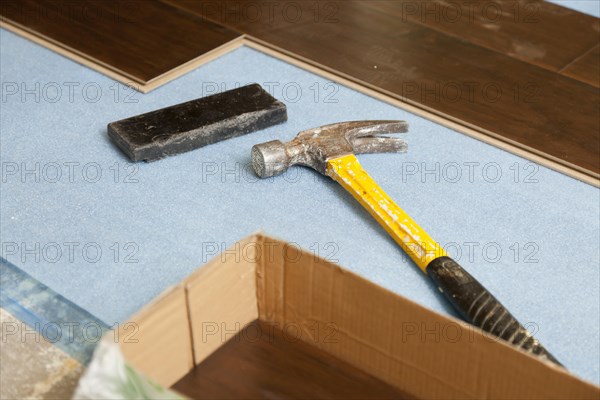 Hammer and block with new laminate flooring abstract