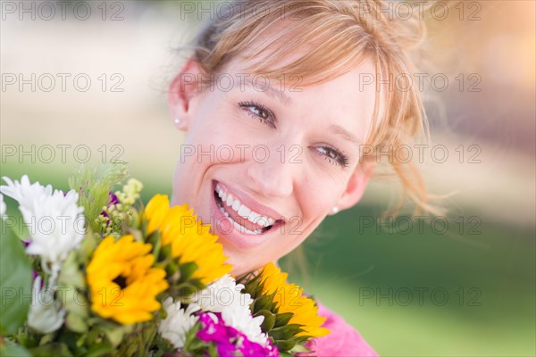 Outdoor portrait of an excited young adult brown eyed woman holding a bouquet of flowers