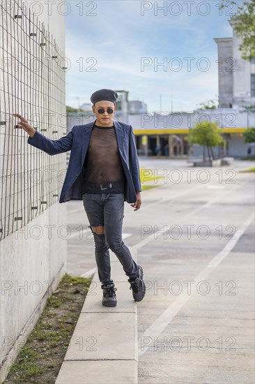 Latin gay male with makeup wearing fashion hat doing catwalk in the street