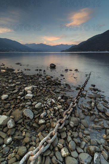 Rusty chain on gravel leads into the water