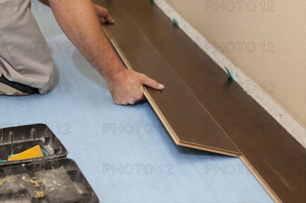 Man installing new laminate wood flooring abstract