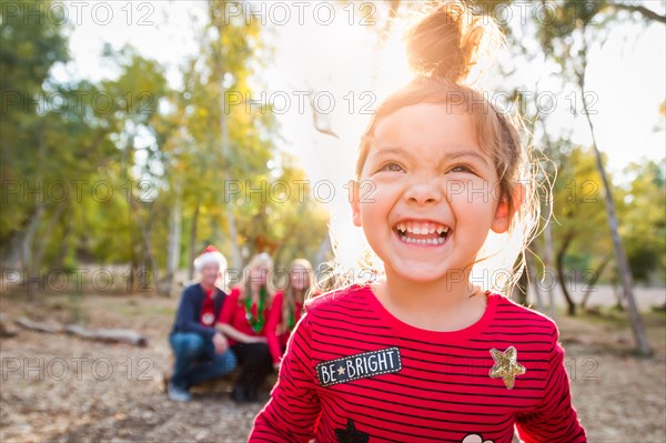 Cute mixed-race baby girl christmas portrait with family behind outdoors