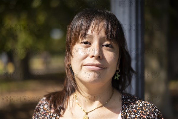 Portrait of a young Latin woman in a park leaning on a lamppost