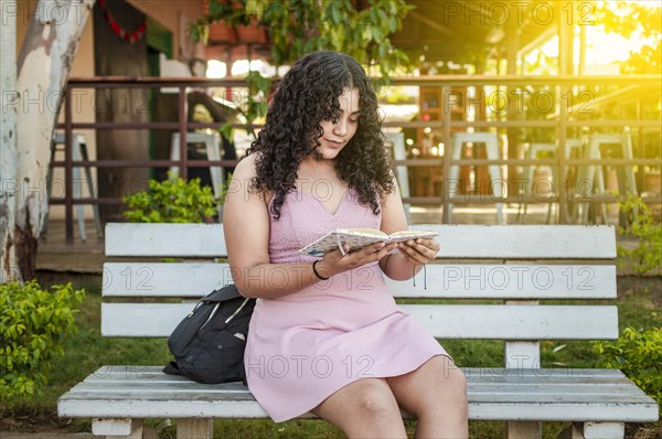 A cute girl sitting on a bench reading a book