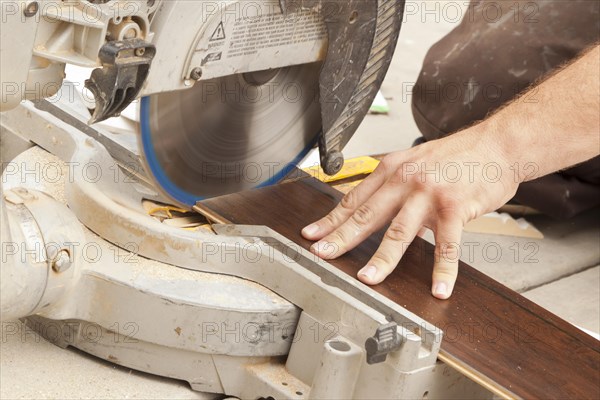 Contractor using circular saw cutting of new laminate flooring renovation