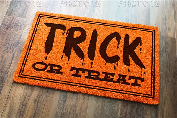 Trick or treat halloween orange welcome mat on wood floor background