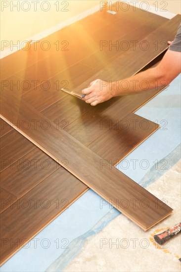 Man installing new laminate wood flooring abstract