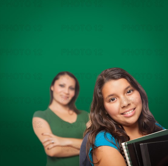 Blank chalk board behind proud hispanic mother and daughter student