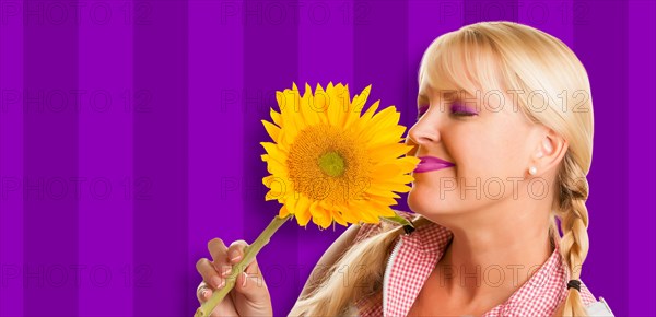 Beautiful girl holding yellow sunflower against purple striped background