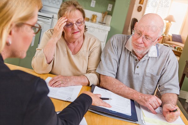 Senior adult couple going over documents in their home with agent at signing