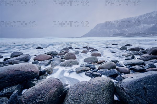 Waves of Norwegian sea surging on stone rocks at Unstad beach