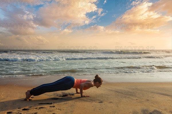 Beautiful sporty fit woman practices Ashtanga Vinyasa yoga Surya Namaskar Sun Salutation asana Chaturanga Dandasana