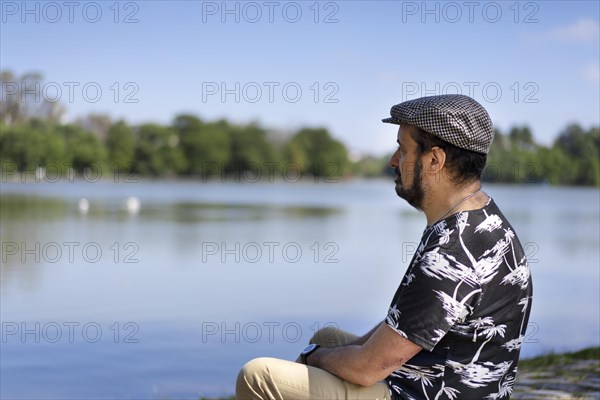 Portrait of a man sitting relaxed contemplating a lake. Copy space