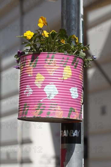 Colourfully painted tin can as a flower pot