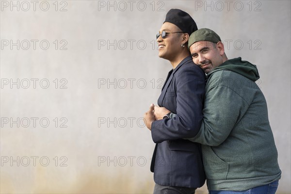 Gay latin couple wearing fashionable hats hugging in the street. Copy space