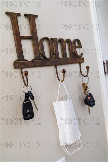 Home key hanger rack next to door with keys and medical face mask during coronavirus pandemic