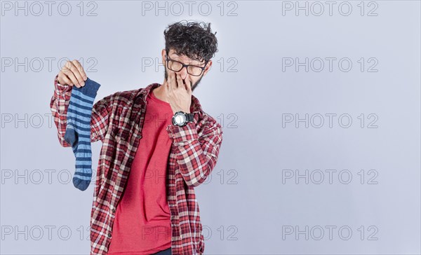 A man with a sock in his hand covering his nose