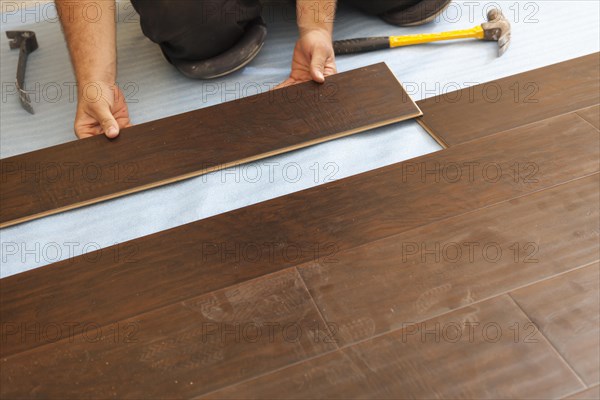 Man installing new laminate wood flooring abstract