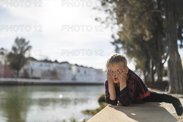 Cute small boy doing funny faces in his free time by the river