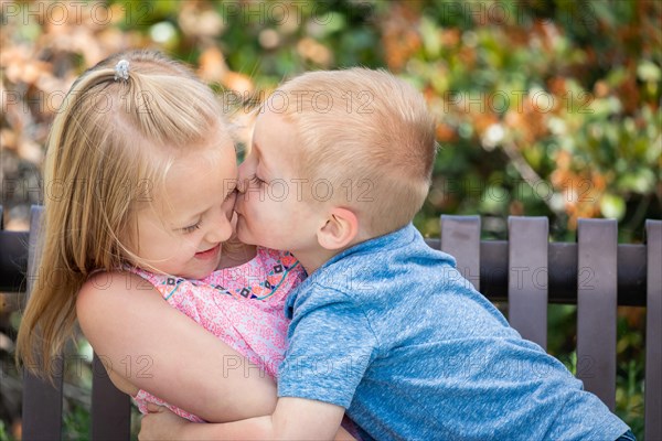 Young sister and brother having fun on the bench at the park