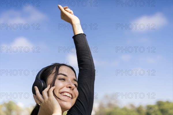 Young woman listening to music outdoors with headphones. Expression of happiness