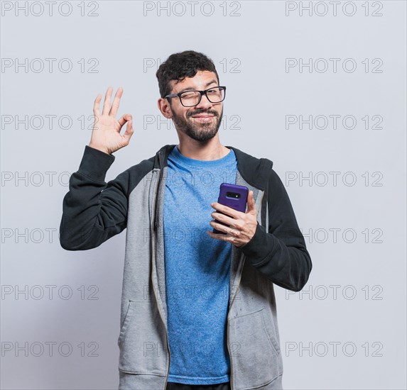 Pleasant person holding cellphone and winking