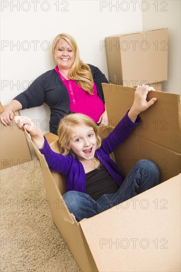 Playful young family in empty room playing with moving boxes