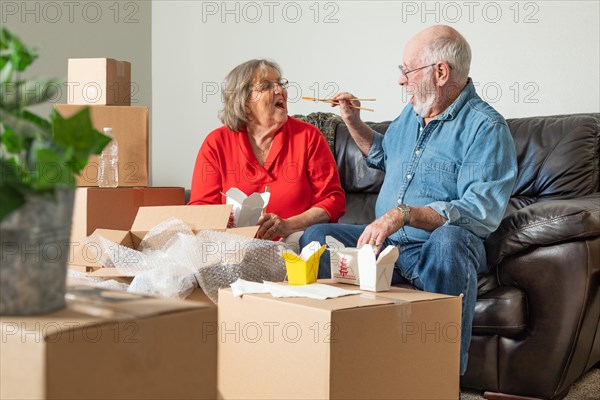 Senior couple enjoying chinese food surrounded by moving boxes