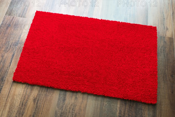 Blank red welcome mat on wood floor background ready for your own text