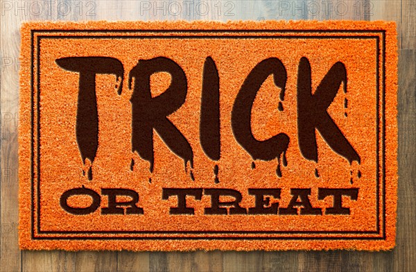 Trick or treat halloween orange welcome mat on wood floor background