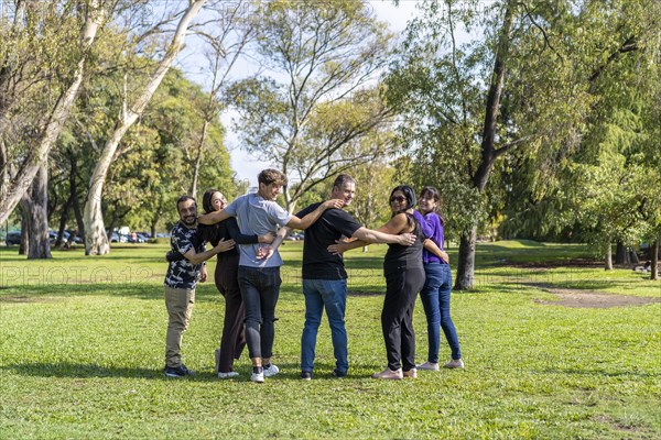 Multi ethnic family group walking arm in arm in a park