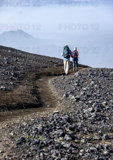 Two hikers on trail through volcanic landscape