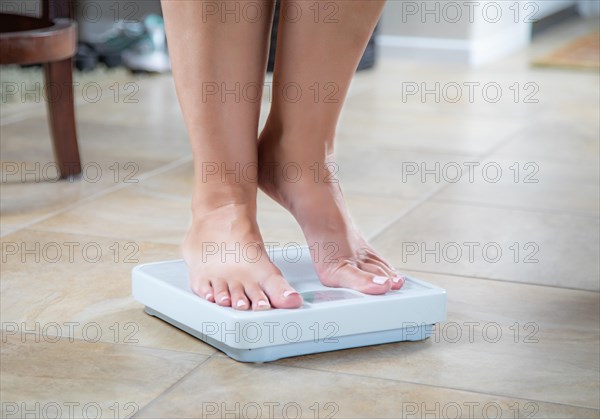 Woman standing on weight scale at home