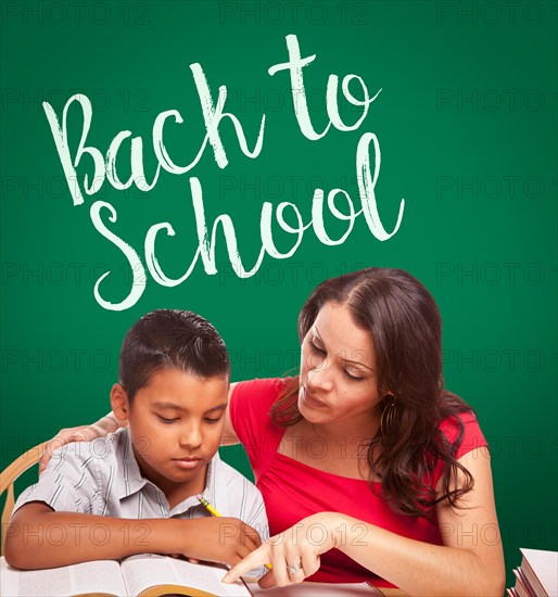 Back to school written on chalk board behind hispanic young boy and famale adult studying