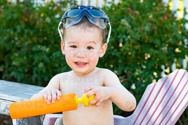 Happy playful young mixed-race chinese and caucasian boy wearing swimming goggles
