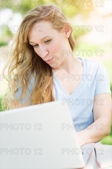 Young adult woman live video chatting outdoors using her laptop