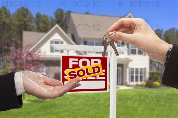 Real estate agent handing over the house keys in front of a beautiful new home