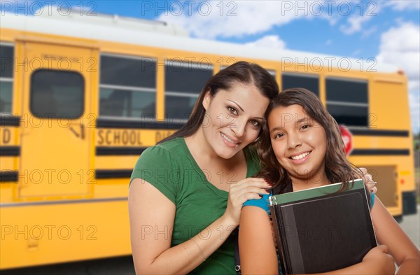 Hispanic mother and daughter near school bus