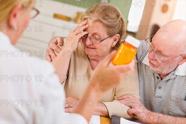 Doctor or nurse explaining prescription medicine to senior adult couple