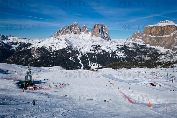 View of a ski resort piste with people skiing in Dolomites in Italy